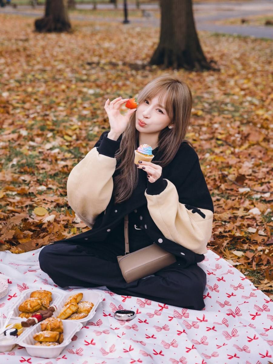 這套造型的關鍵，在於用「深色打底＋淺色外層」把比例悄悄往上提。內搭以全黑套裝為主，線條乾淨、沒有多餘切割，視覺自然一路向下延伸；外層則選擇米色拼接的棒球外套，淺色集中在上半身，成功把視線拉高。棒球外套本身的寬肩輪廓，讓整體看起來更俐落。王心凌以寬鬆剪裁保留輕鬆感，搭配駝色系小巧斜背包作為重心點綴，即使是坐著的畫面，腿部比例依然清楚，是非常適合小隻女孩在日常休閒場合複製的顯高穿法。