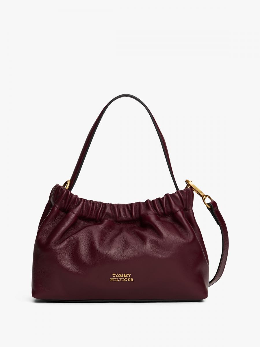 這款酒紅色斜背包以柔軟納帕皮革打造，細膩光澤與自然垂墜的褶襉設計，讓包型在俐落中多了一分優雅鬆弛感。簡潔線條搭配正面低調的 Tommy Hilfiger 品牌識別牌，質感恰到好處，不張揚卻很耐看。22 × 8 × 15 公分的實用尺寸，搭配可拆式斜背肩帶與內部拉鍊口袋，無論日常外出或節慶穿搭都相當合適，是一款兼顧造型與機能性的高完成度單品。