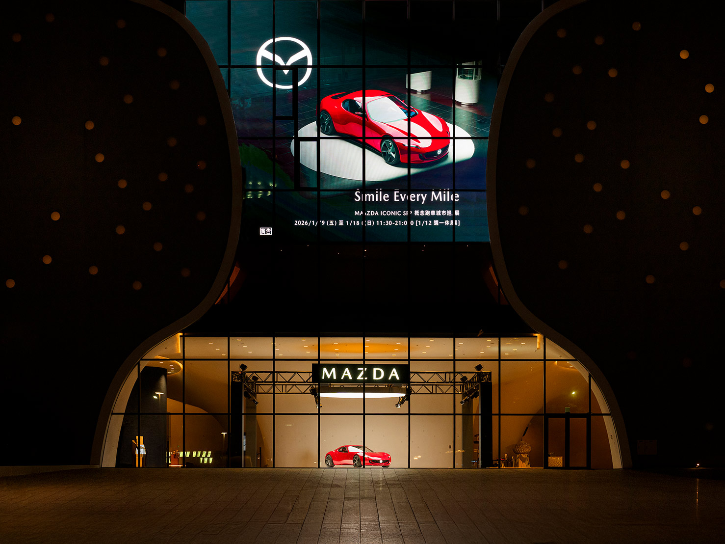 穿梭於臺中國家歌劇院之中，緩緩書寫 ICONIC SP 概念跑車的極致美學。MAZDA 以全新品牌精神「Smile Every Mile」作為參展主軸，將駕馭樂趣從移動本身延伸至觀展體驗，構築富含情感共鳴的旅程式敘事。大面積清透玻璃引入自然光線，映照於車身之間，藉由流暢的車身線條，回應有機的建築語彙，揉合國際級文化地標的設計美學。透過觀者的視角，探索建築、速度與工藝間的共鳴，待你推開臺中國家歌劇院之門，讓每段旅程，樂趣紛呈。
