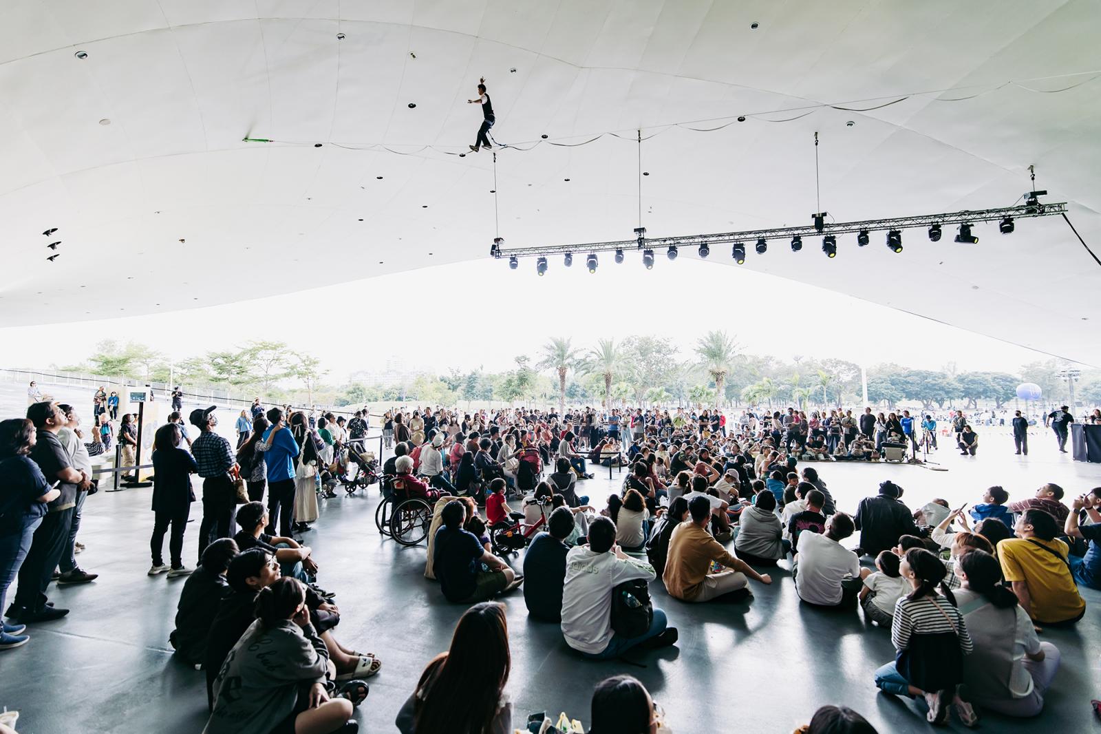 作為台灣指標性的表演藝術場館，衛武營在硬體條件上本就具備明確的國際水準。由荷蘭建築師 Francine Houben 法蘭馨候班設計的場館，以在地榕樹群為靈感，轉化為流動的白色曲線屋頂與開放式「榕樹廣場」，在空間語彙上跳脫傳統劇院的封閉結構，形塑更具開放性的公共場域。場館內部則規劃四座符合國際規格的表演空間，其中最具代表性的音樂廳採用葡萄園式座席配置，環繞舞台的結構設計，帶來完整而均衡的聲學體驗。這種同時兼顧建築美感與專業技術的場館條件，使衛武營在國際藝術家與製作團隊眼中，具備與歐洲一線劇院交流合作的實力，也讓勞力士的文化夥伴關係，能真正落實於高水準的演出內容中。