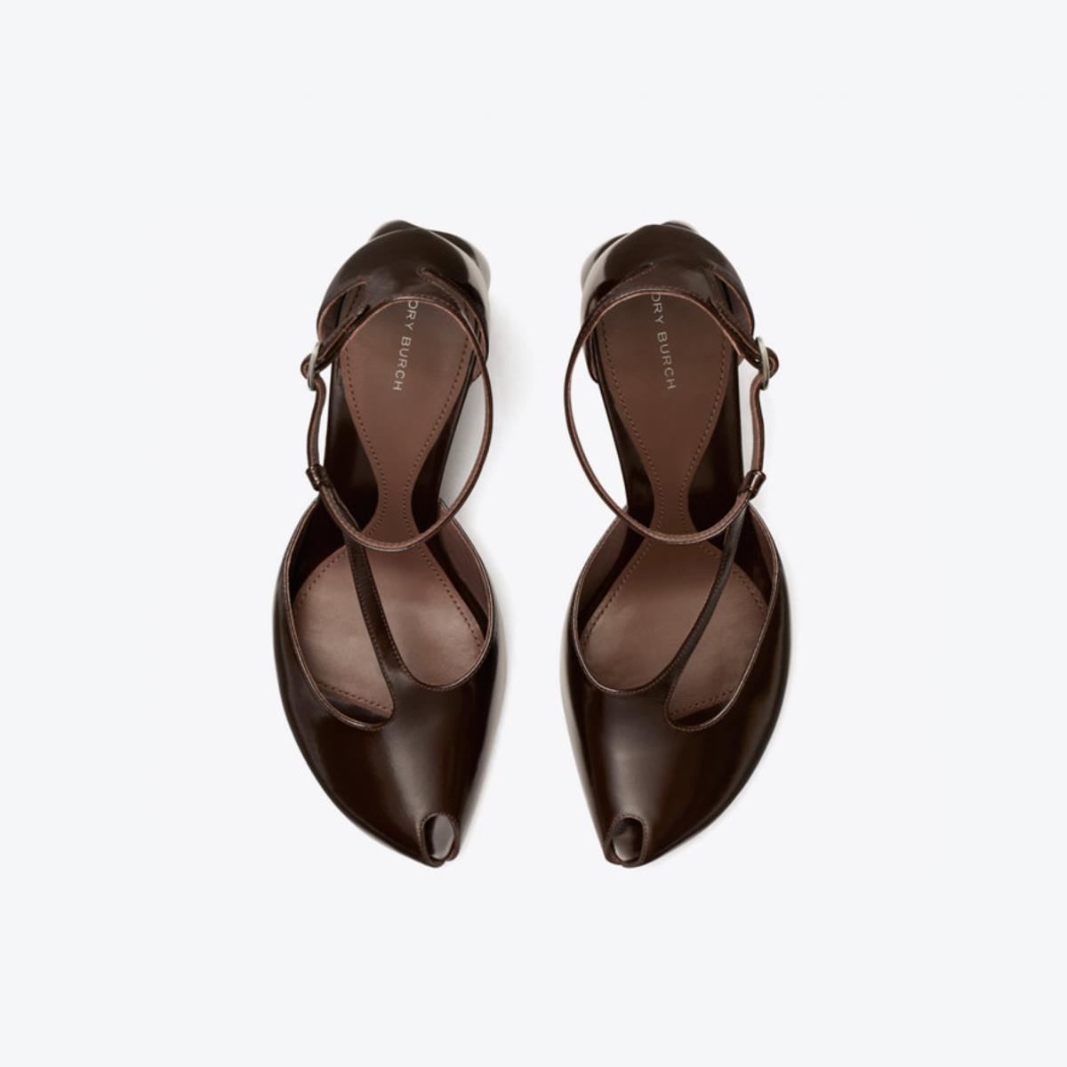 這雙露趾 T 字帶高跟涼鞋，將性感拆解為結構與比例的精準拿捏。T 字帶設計在視覺上自然延伸腿部線條，露趾剪裁則替整體注入輕盈感，即使搭配高跟也不顯厚重。鞋跟高度刻意收斂，讓行走時仍保有穩定與舒適。它是一雙能從白天一路穿到晚上的實用款式，搭配洋裝時展現優雅線條，與褲裝組合則能柔化輪廓、強調女性曲線，非常推薦給都會摩登女性。