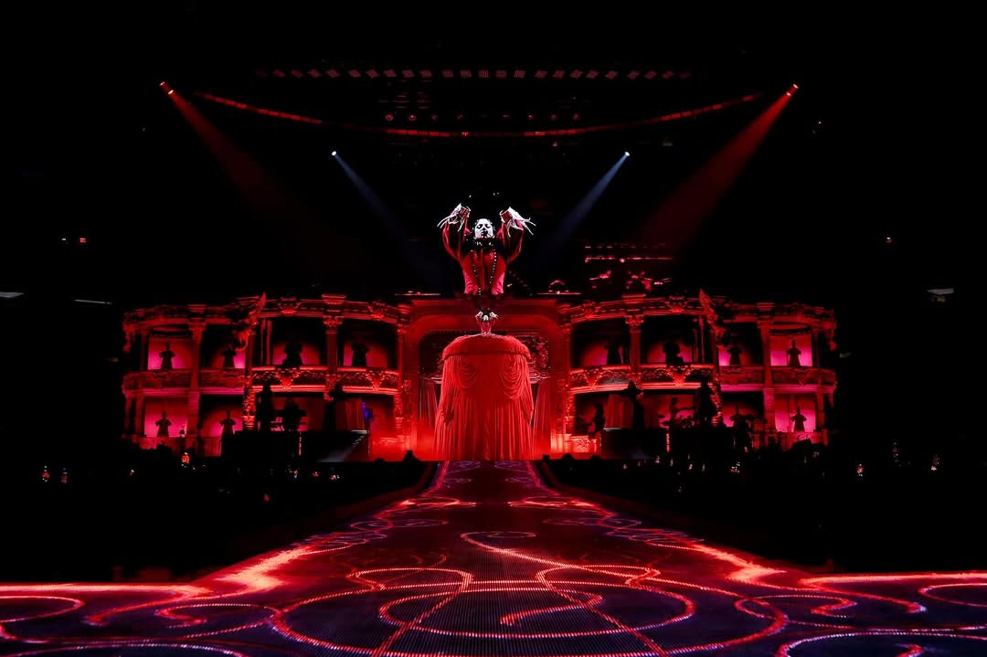 此次舞台上 Lady Gaga 所穿的 Alexander McQueen 服裝，以鳥籠造型作為頭飾，搭配紅色羽毛上衣，呈現出高度戲劇張力的視覺效果。